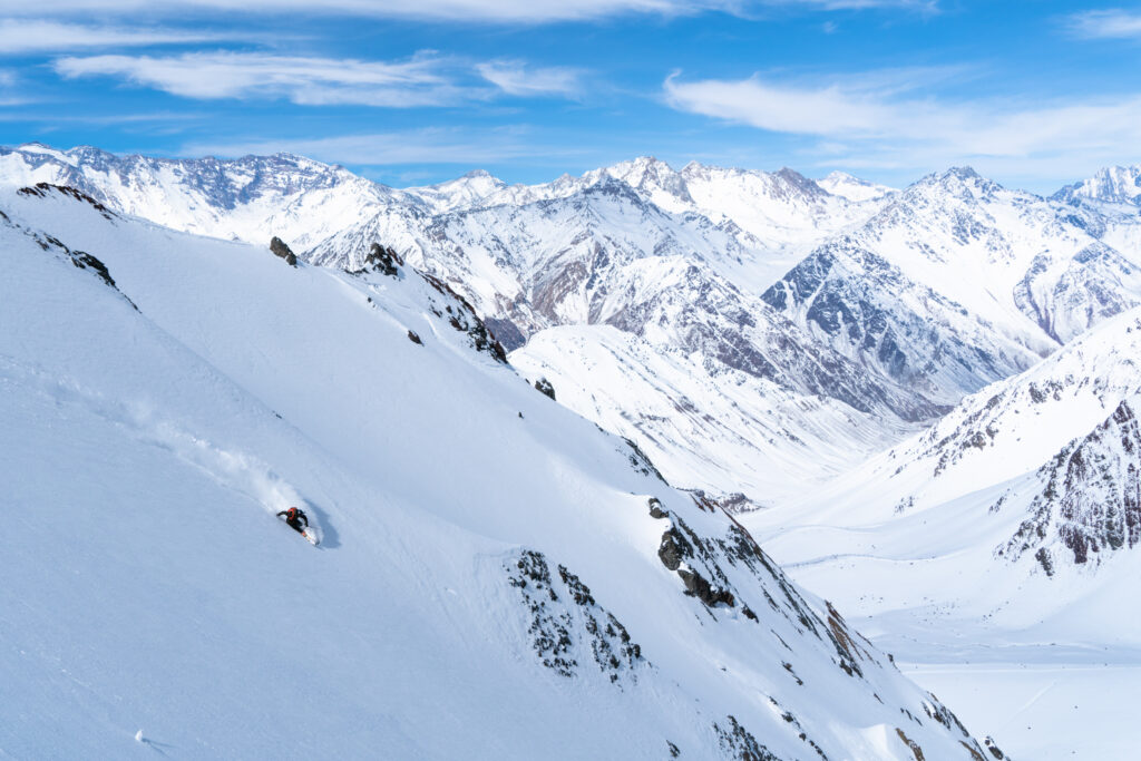 A skier makes beautiful fresh tracks down a pristine face, high in the mountains