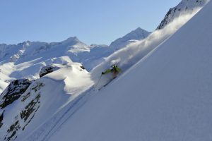 A freeride skier has found a sweet, deep, untracked backcountry area to spray snow down, high in the mountains judging on the snowy peaks surrounding...