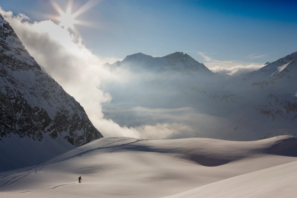 lone skier in distance in magical white wild backcountry with a setting sun