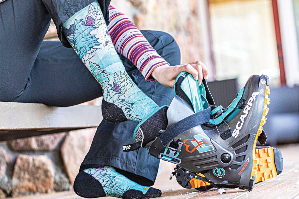 A skier putting on Smartwool socks and ski boots