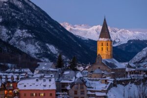 baqueira beret town at dusk with a church steeple dominating the scene against a backdrop of snowy mountains