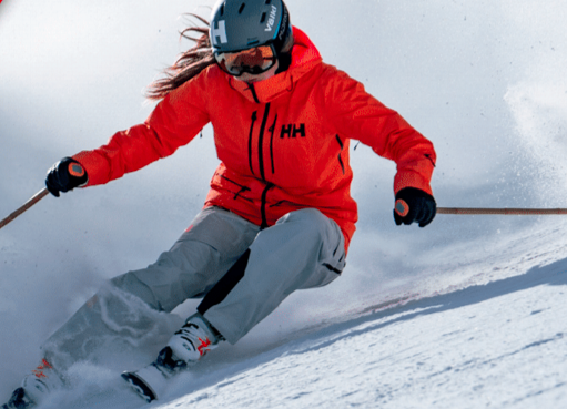 woman skis in orange helly hansen jacket with fantastic form on edges of ski