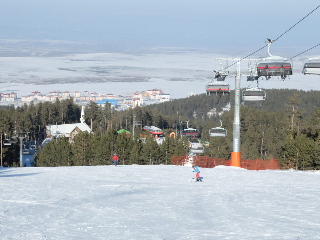 classic ski resort scene in turkey with resort in valley and skiers and chairlift in the foreground
