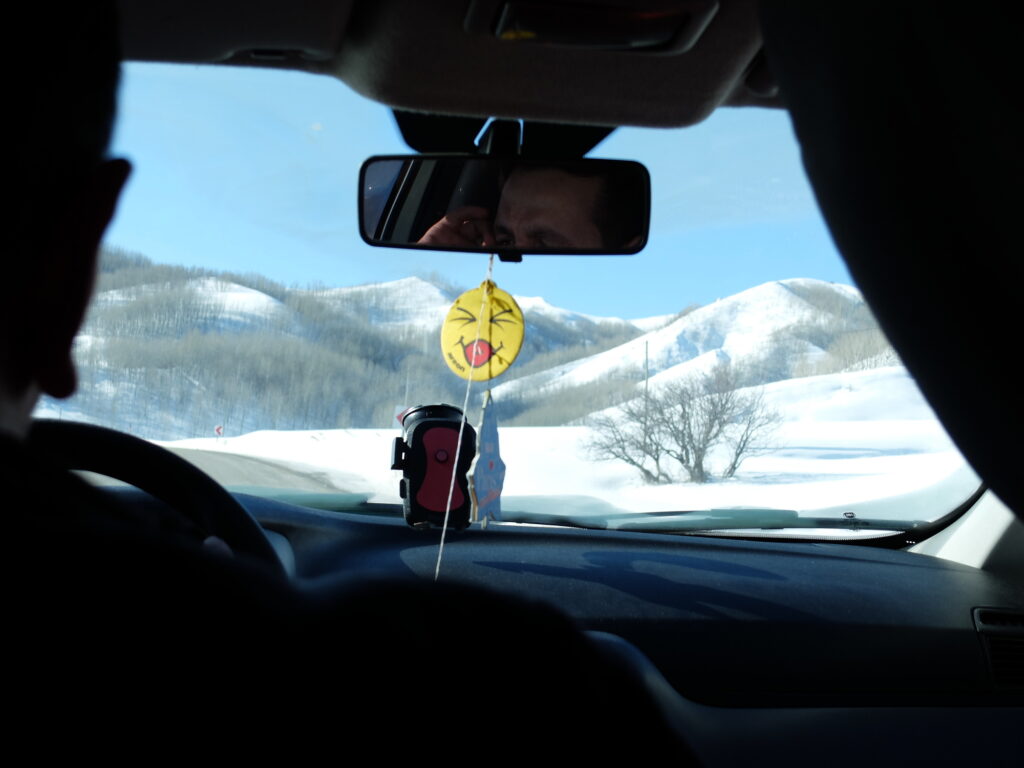 snow outside the car, photo taken from inside through windscreen. smiley car freshener dominates picture