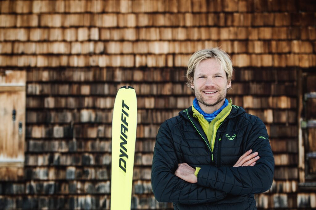 dynafit general manager stands in front of a wood ski lodge blurred in background with a dynafit ski in a profile photo