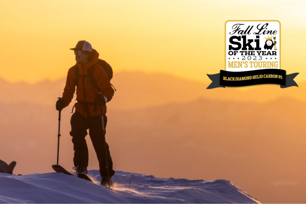 yellow and orange dusk (or dawn) ski tour. Skier is walking near the top of a mountain in front of a sunrise