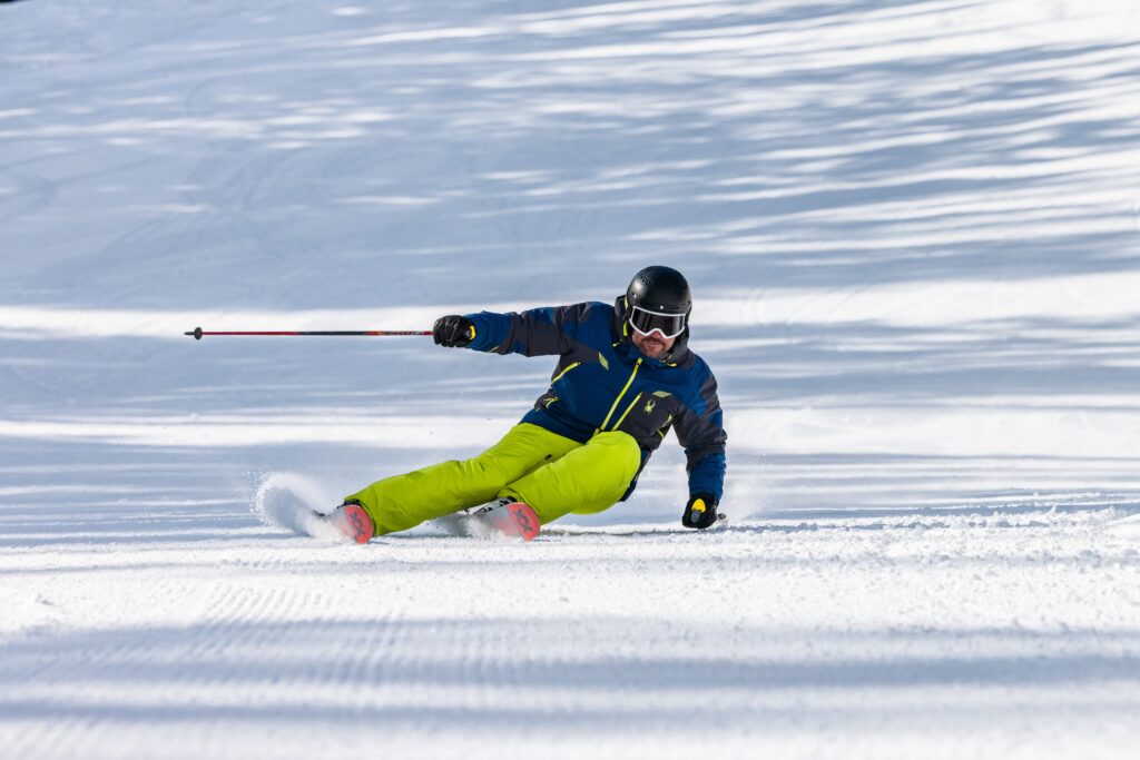 skier carves down a piste kitted out in Spyder yellow pants and a blue jacket