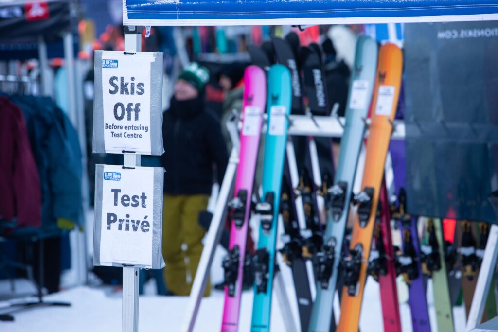 signs read 'skis off' at entrance to test centre with stacks of skis behind
