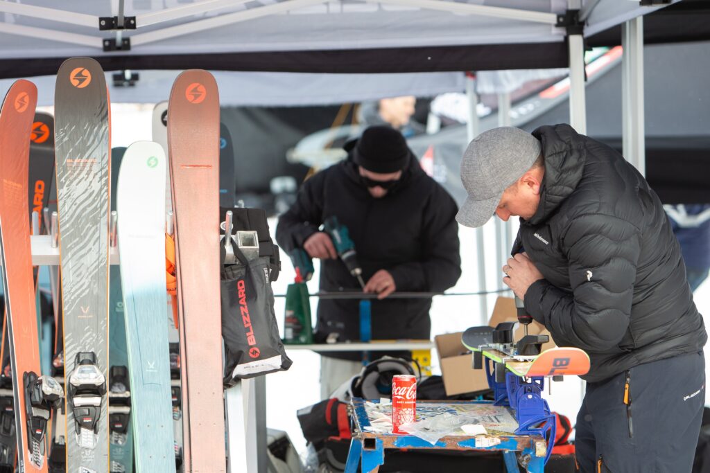 two guys work on fixing bindings to skis and servicing
