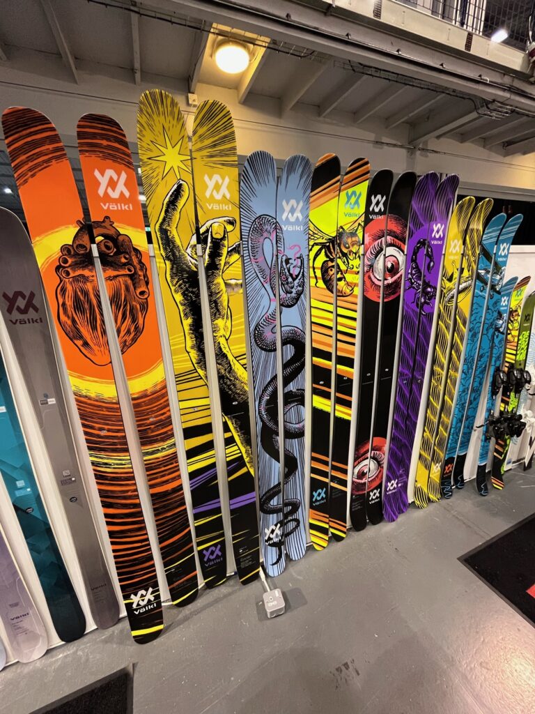 line up of fat skis in a tradeshow shop with wacky designs and no bindings