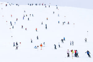 a ski piste full of skiers like ants dotted all over the hill