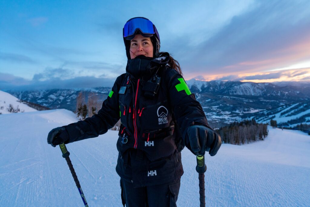 big sky female ski patroller rachel efta stands on mountain during sunset in black uniform