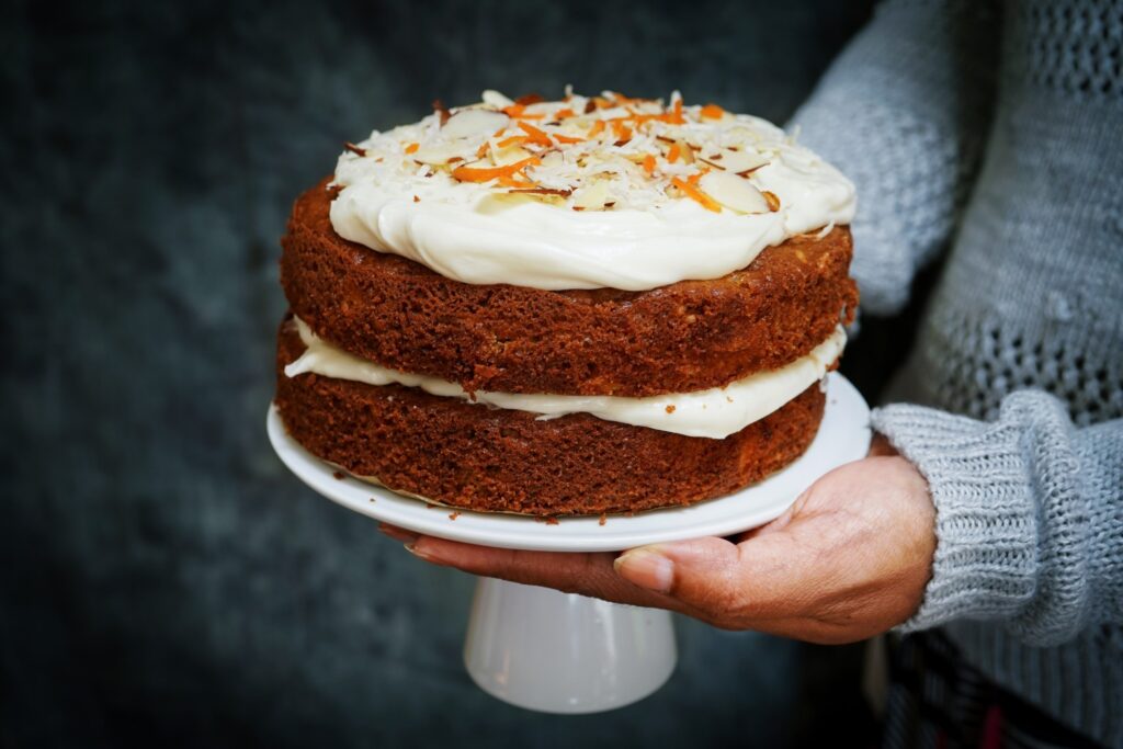 pro food mage of a carrot cake on a stand with icing and sprinkles