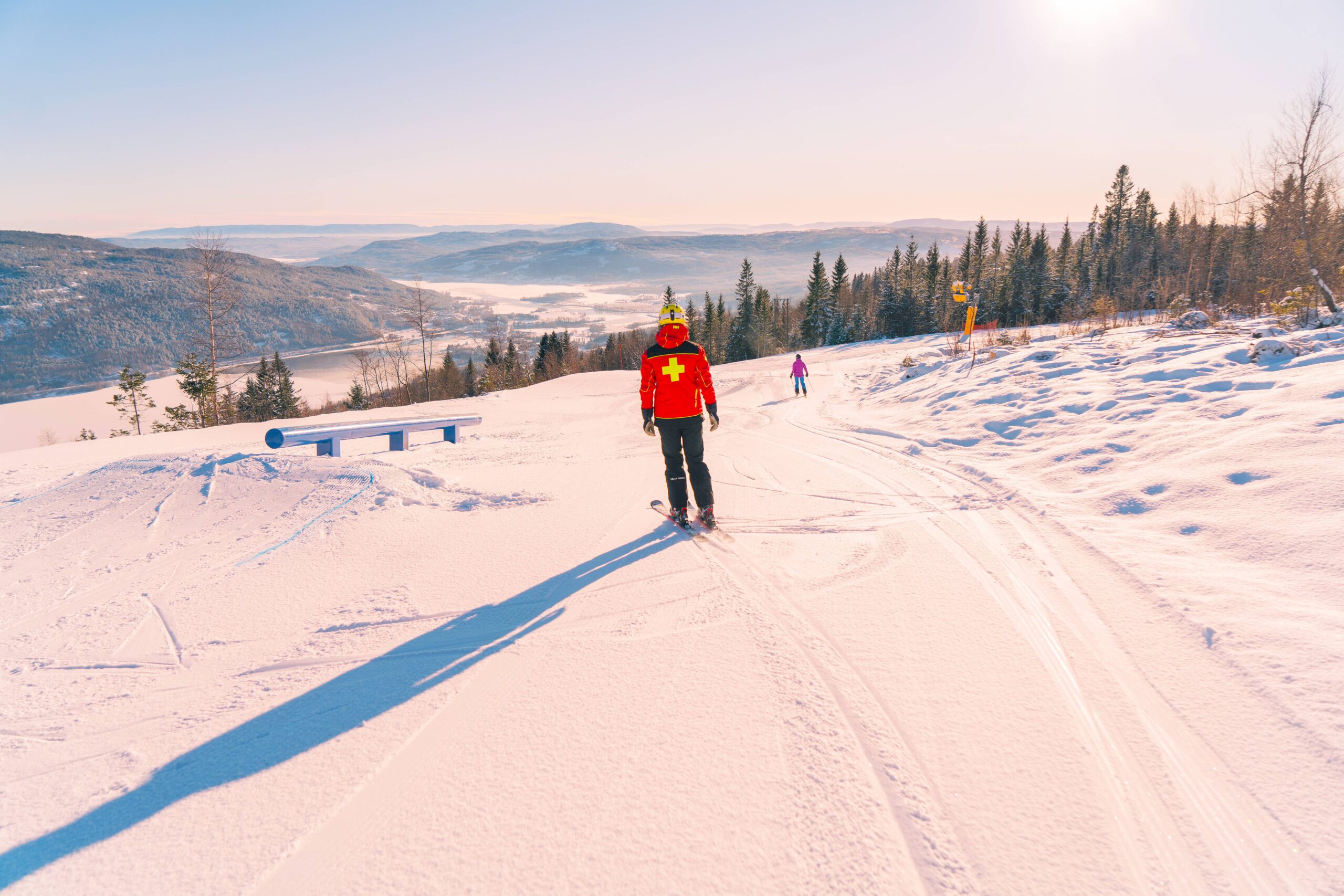 ski patroller skies off on a flat slope with warm light on piste