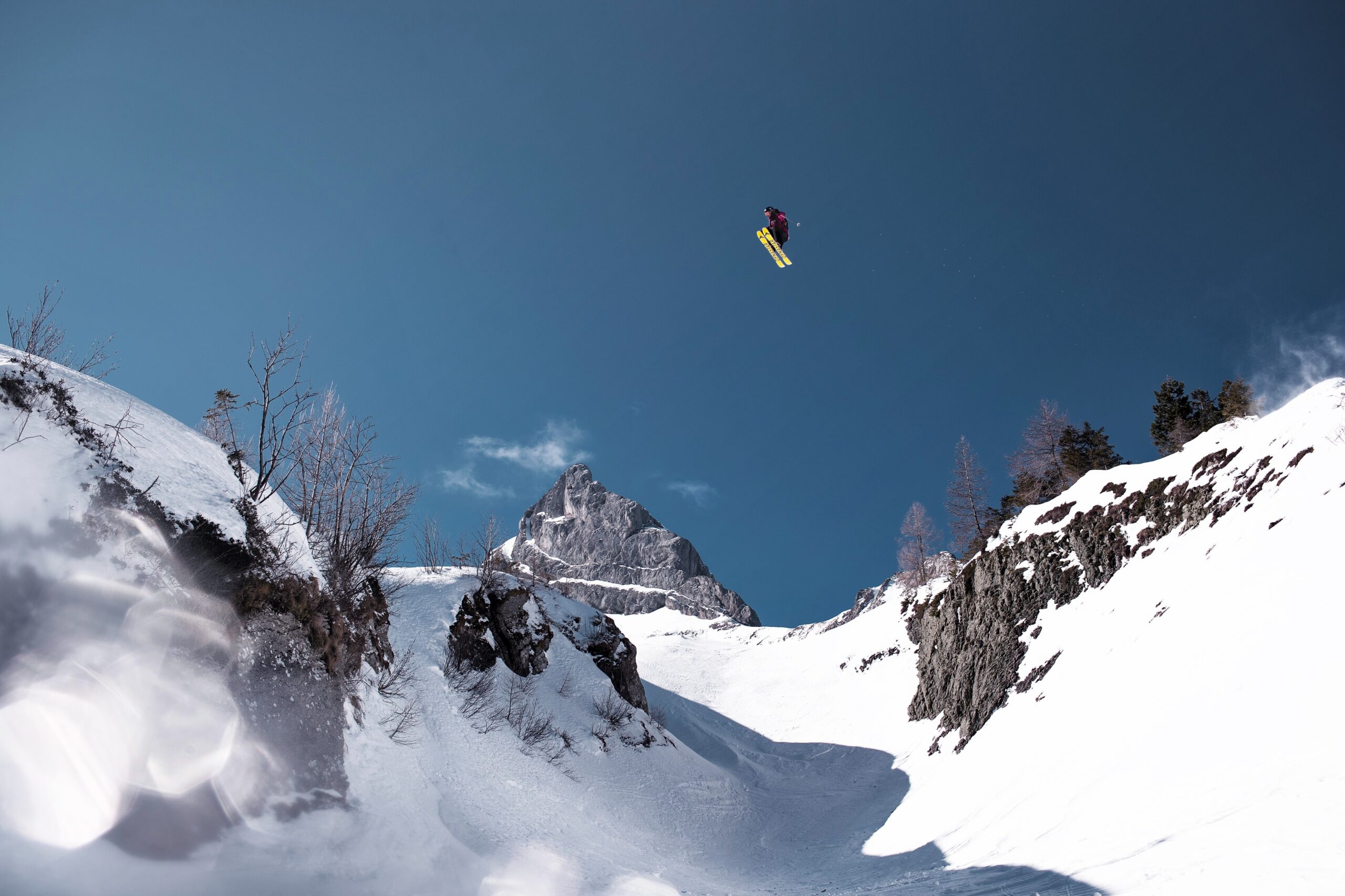 skier with huge air jumping a gap between rocks over snow