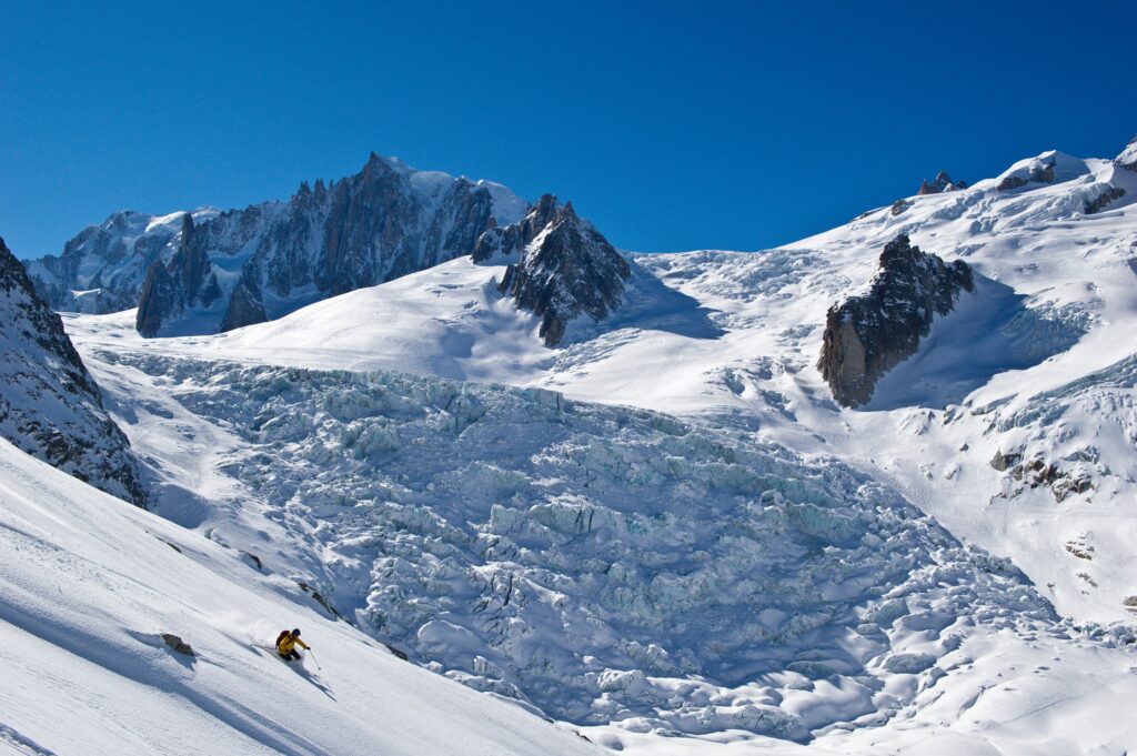 a tiny skier turns down the Vallee Blanche descent in front of the huge glacier