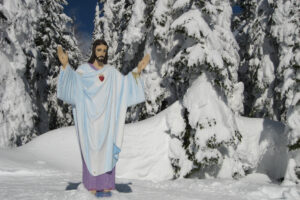 Human size Jesus statue stands in front of snowy trees