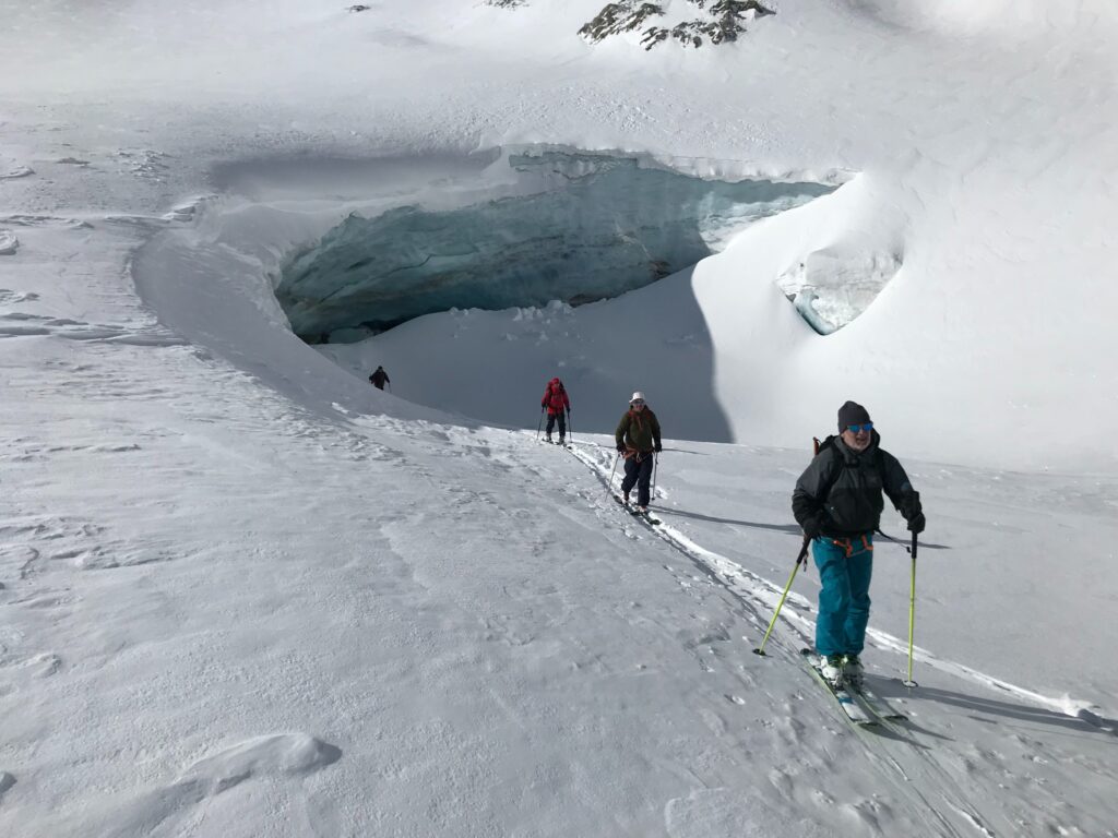 four ski tourers skinning out of a glacial cave