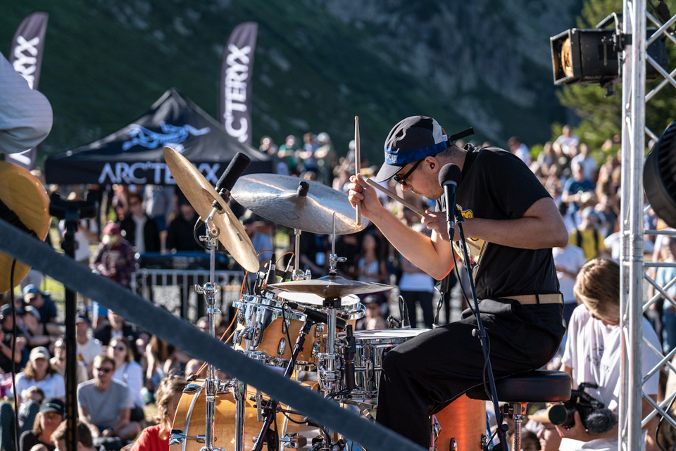 man plays the drums, with a blurred crowd behind, at the Arc'teryx alpine academy in Chamonix - a mountain festival