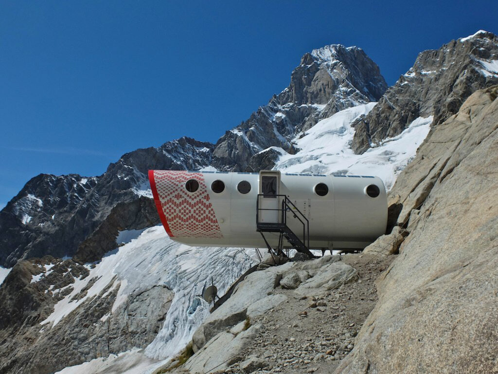 A space age capsule perched on a remote glacier, with snow, peaks and rock surrounding