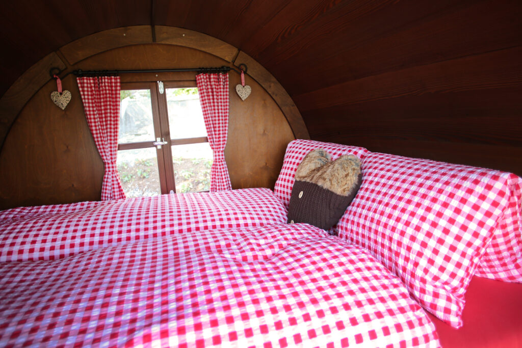 An Austrian looking duvet cover, curtains and heart ornaments adorn a tiny wood cabin