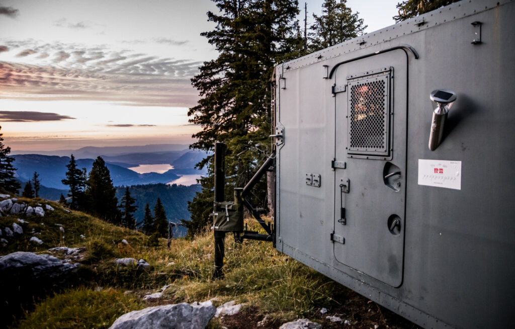 A metal container is accommodation, positioned in the most beautiful setting - pictured at dusk looking over a valley of lakes and low mountains