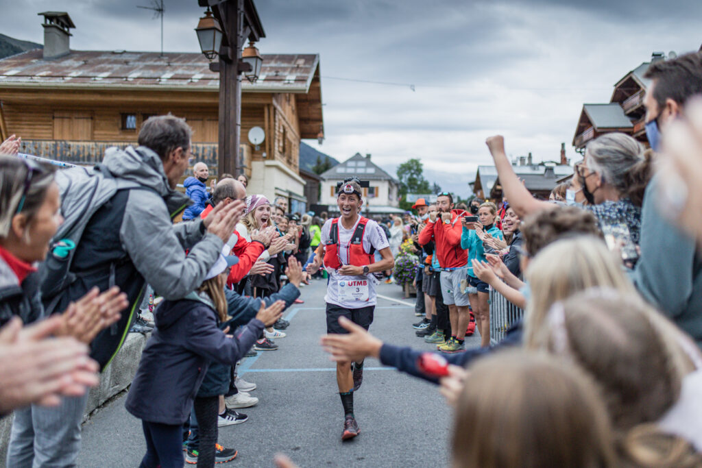 A big crowd either side of the road holds out hands and cheers UTMB runner Courtney Dauwalter