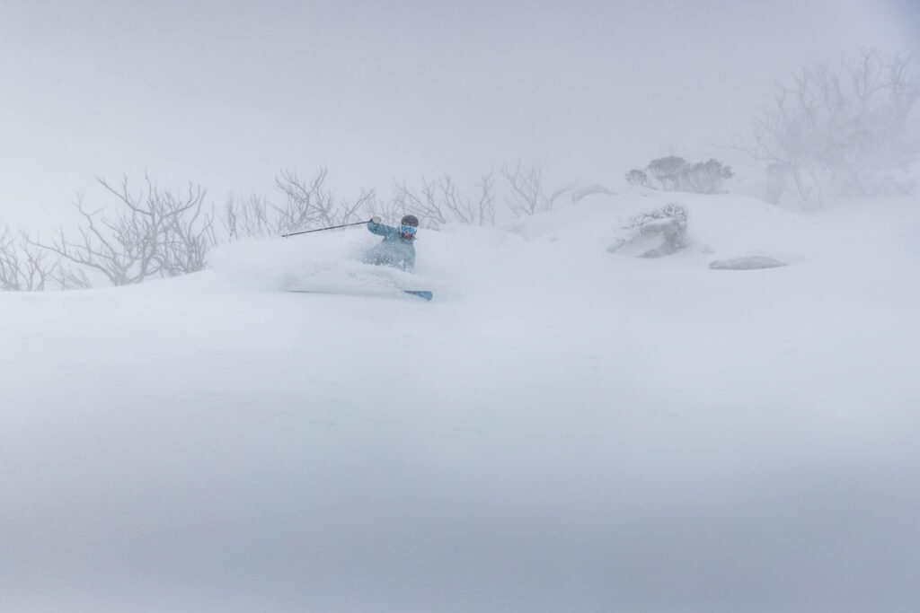 a skier makes a turn in fresh powder, in bad visibility - looks like it's still snowing