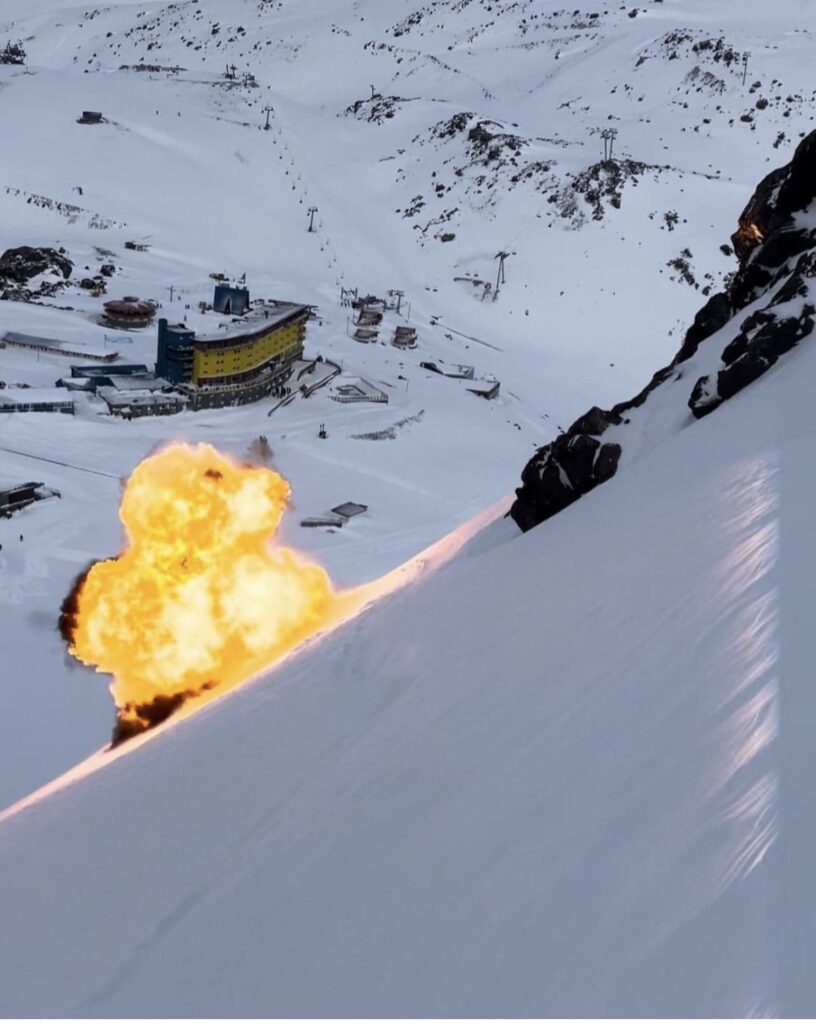 An untouched slope of mountain is pictured above the famous yellow building of Portillo resort in Chile, with a ball of fire burning on the snow - clearly just shot from an avalanche control mission