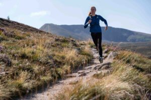 woman running in mountain trail in Scottish landscape