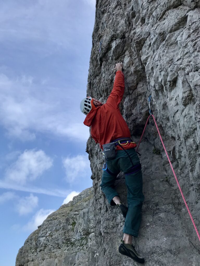 man in red jacket rock climbs