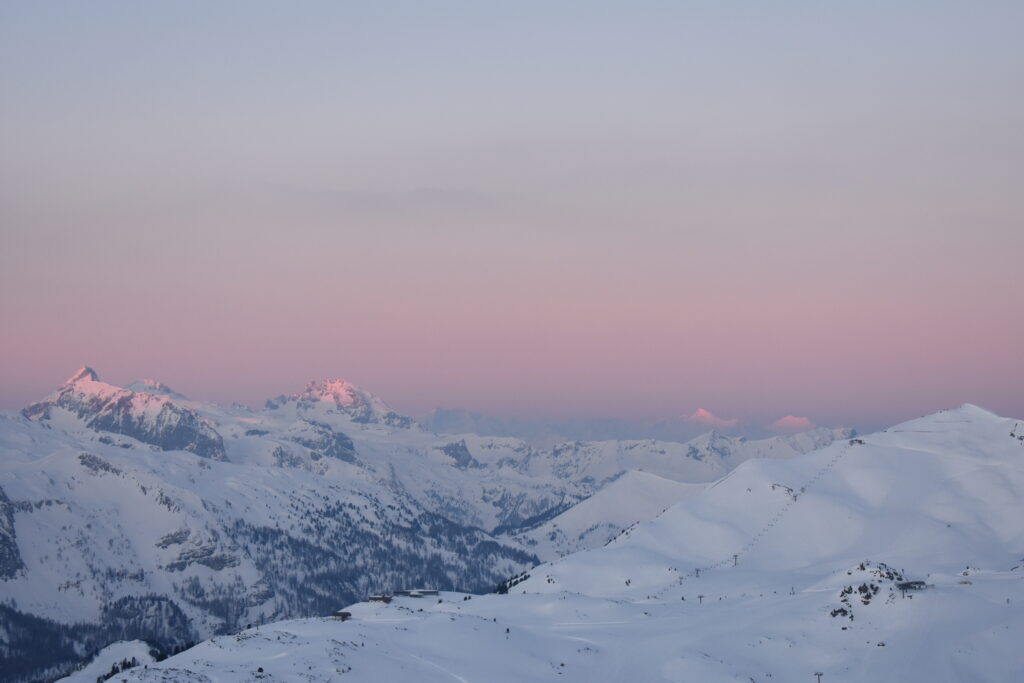 a pinky mountain sunrise over a white mountainscape, photo taken from high mountains at dawn