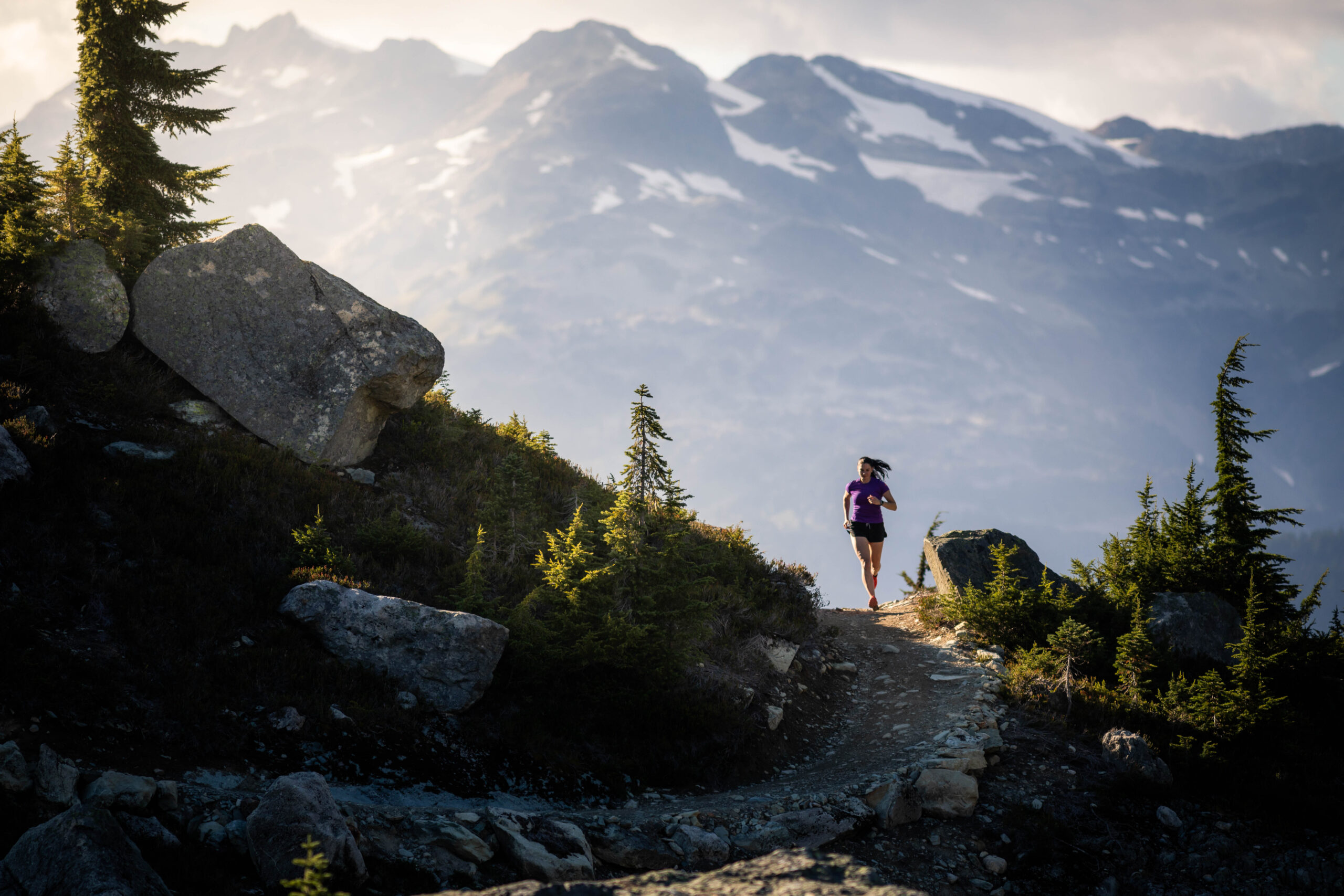 a beautiful high mountain scene of a solo figure running, silhouetted against a big mountain drop