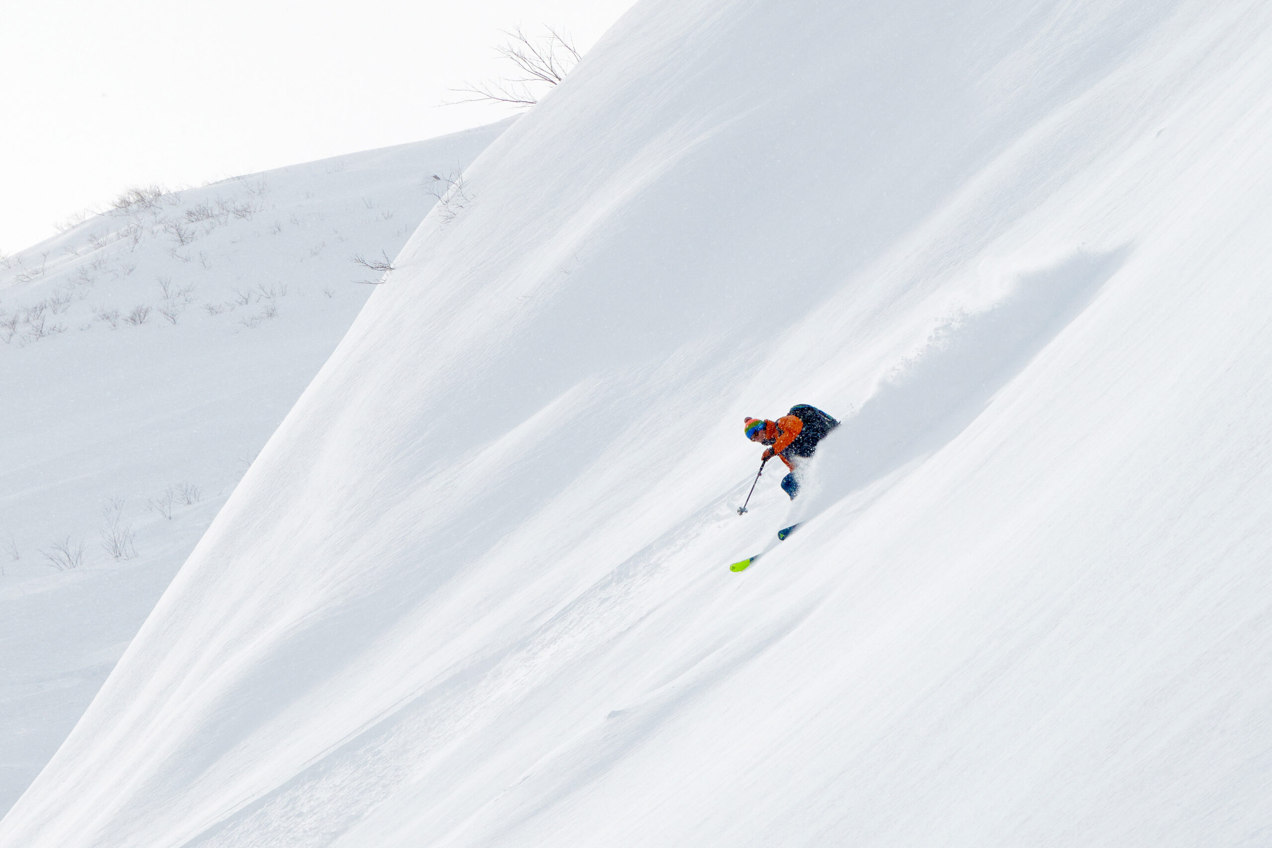 A pristine slope, not a tree in sight, as a skier descends on beautiful light Japow