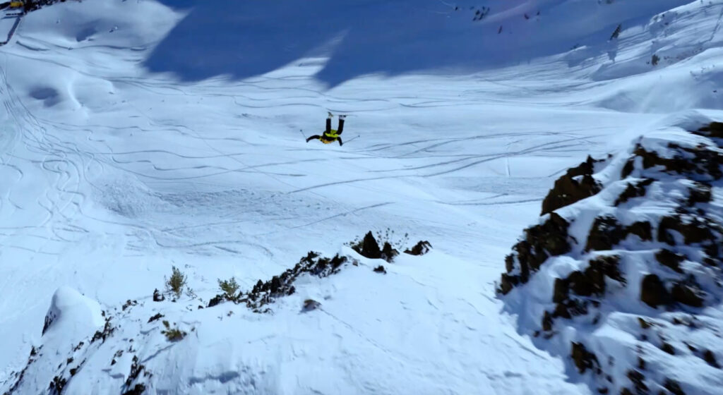 skier mid front somersault hucking off a cliff,