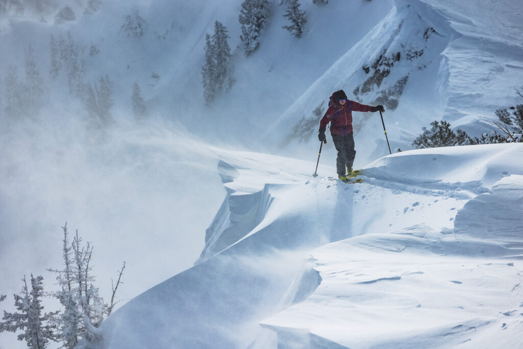 a ski tourer heads uphill on wind affected terrain