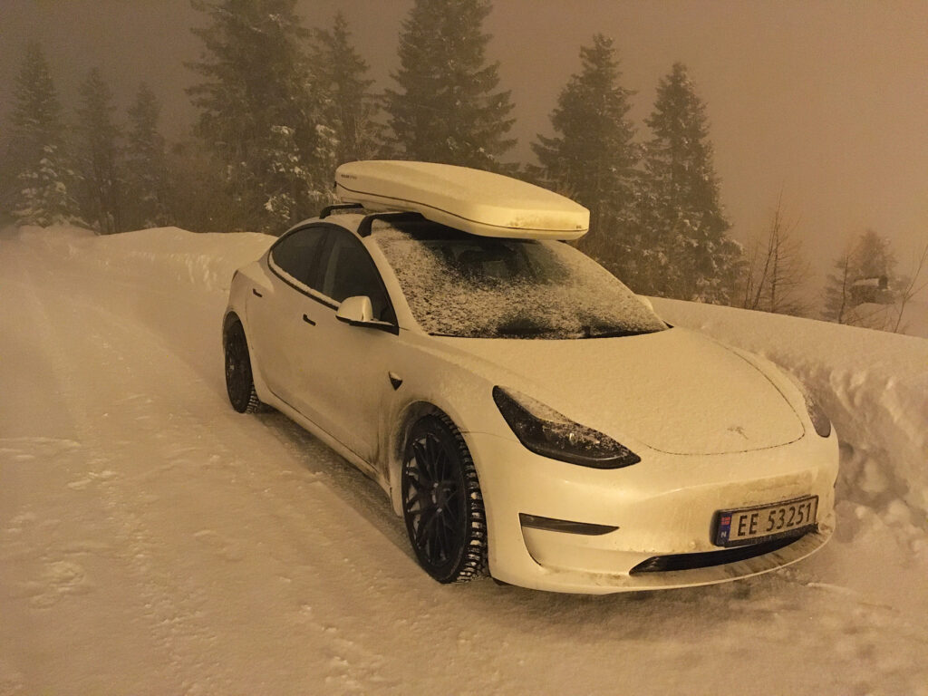 a white tesla in a snowy setting, photo taken in dark with a sepia light