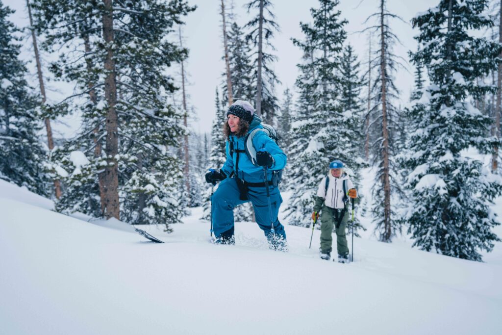 Two ski tourers head upwards in snowy snowy terrain