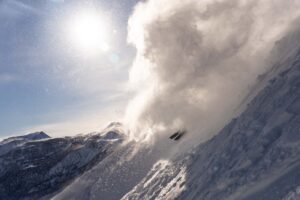 tips of skis only visible in this incredible ski shot of a skier, on a steep, in a cloud of powder snow