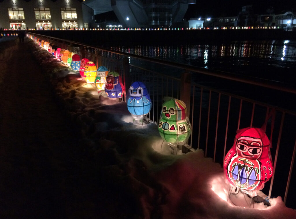 coloured animal lanterns sit on snow at night, lit up
