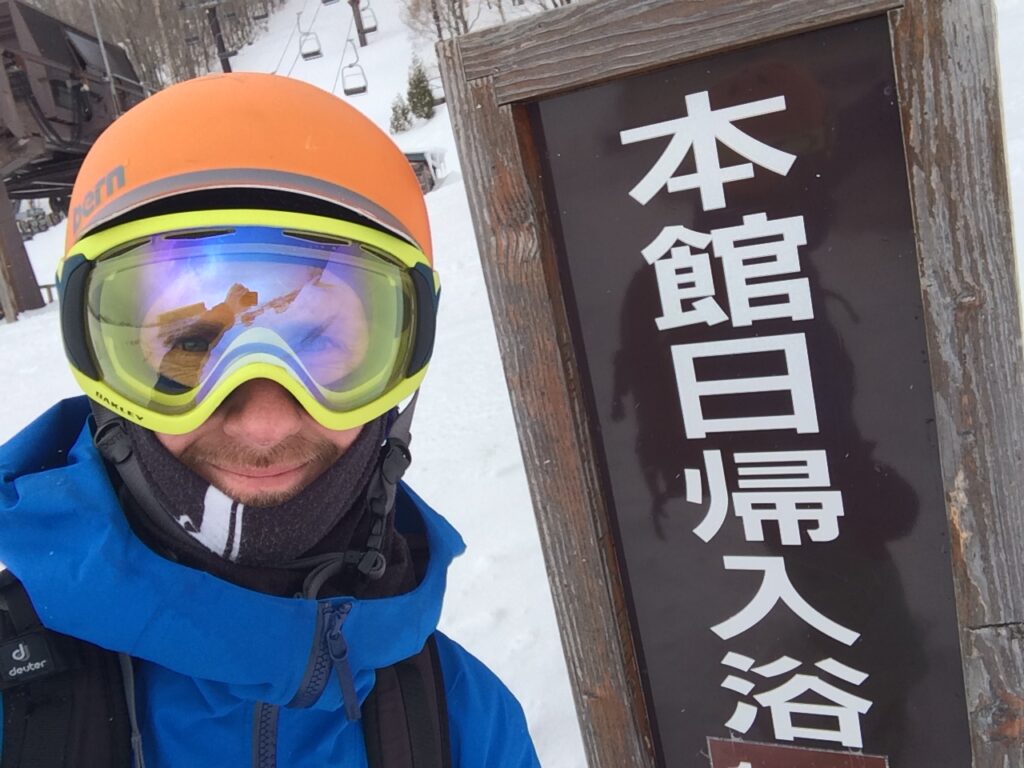 A skier, goggled-up jonny richards, next to a Japanese sign
