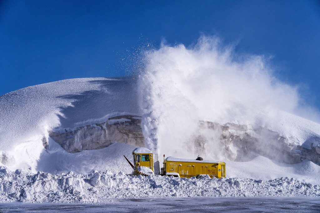 a yellow snow blowing machine pumps out snow, surrounded by the white stuff