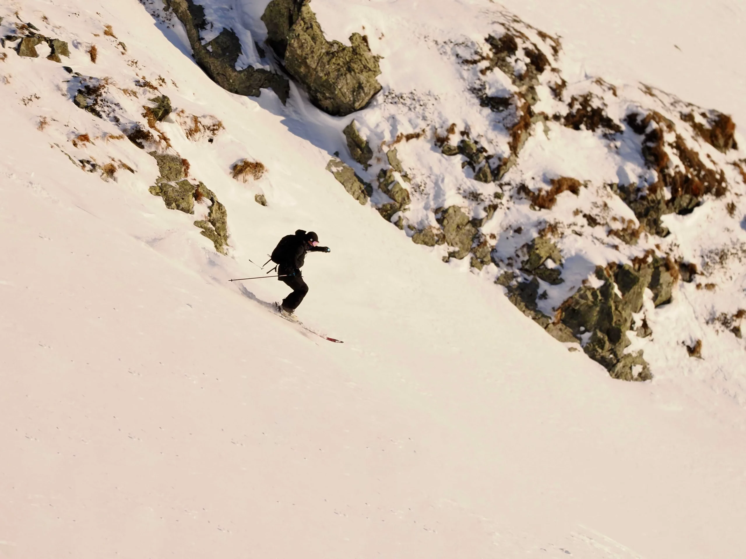 skier on descent by rocks