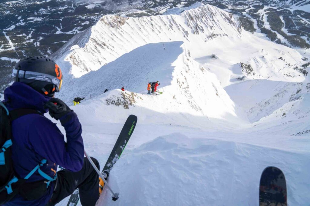 looking over the edge into Big C couloir, a few skiers on the ridge below