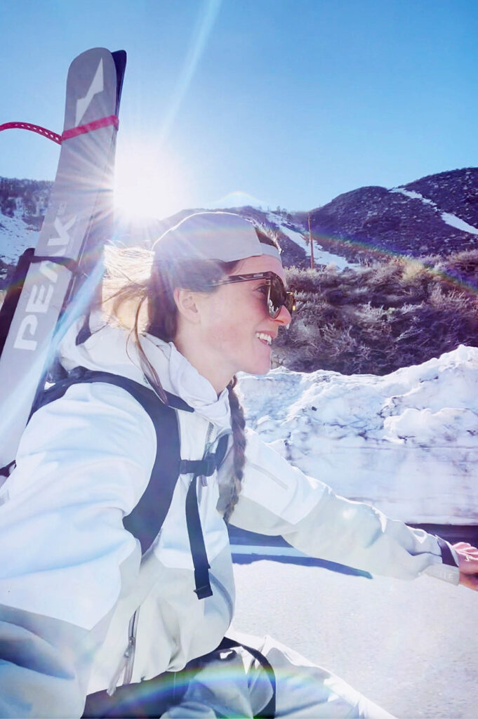 Michelle Parker selfie, skis on back, biking in snowy setting