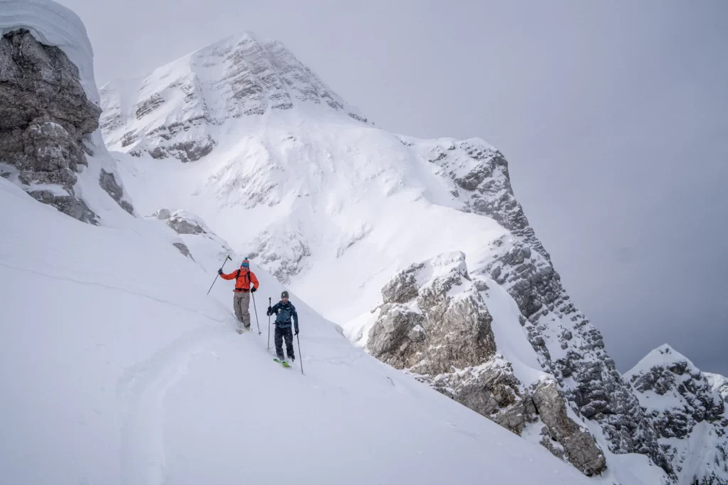 two ski tourers on a fresh cut skin track in the high mountains