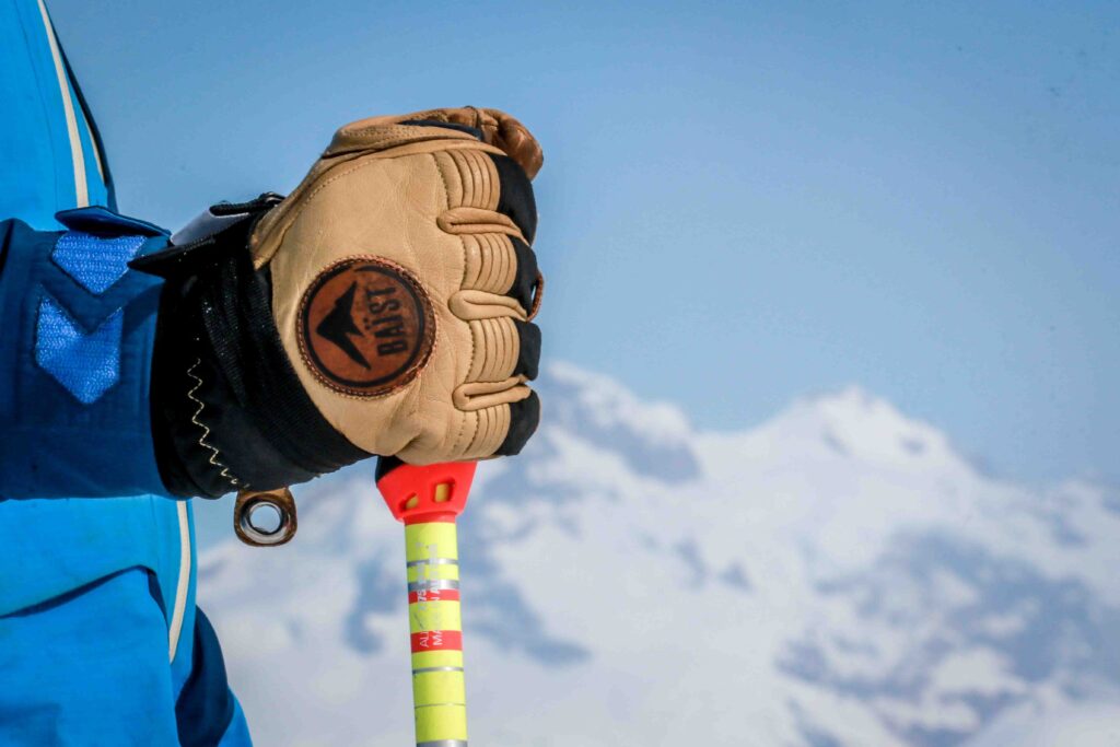 a ski glove focus, holding a pole, with a mountainscape blurred as background