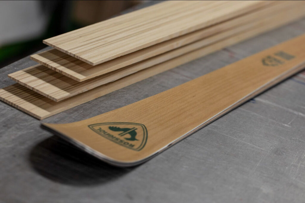 a Rossignol wood-look-lam ski lies flat on a workbench, just the tip in shot