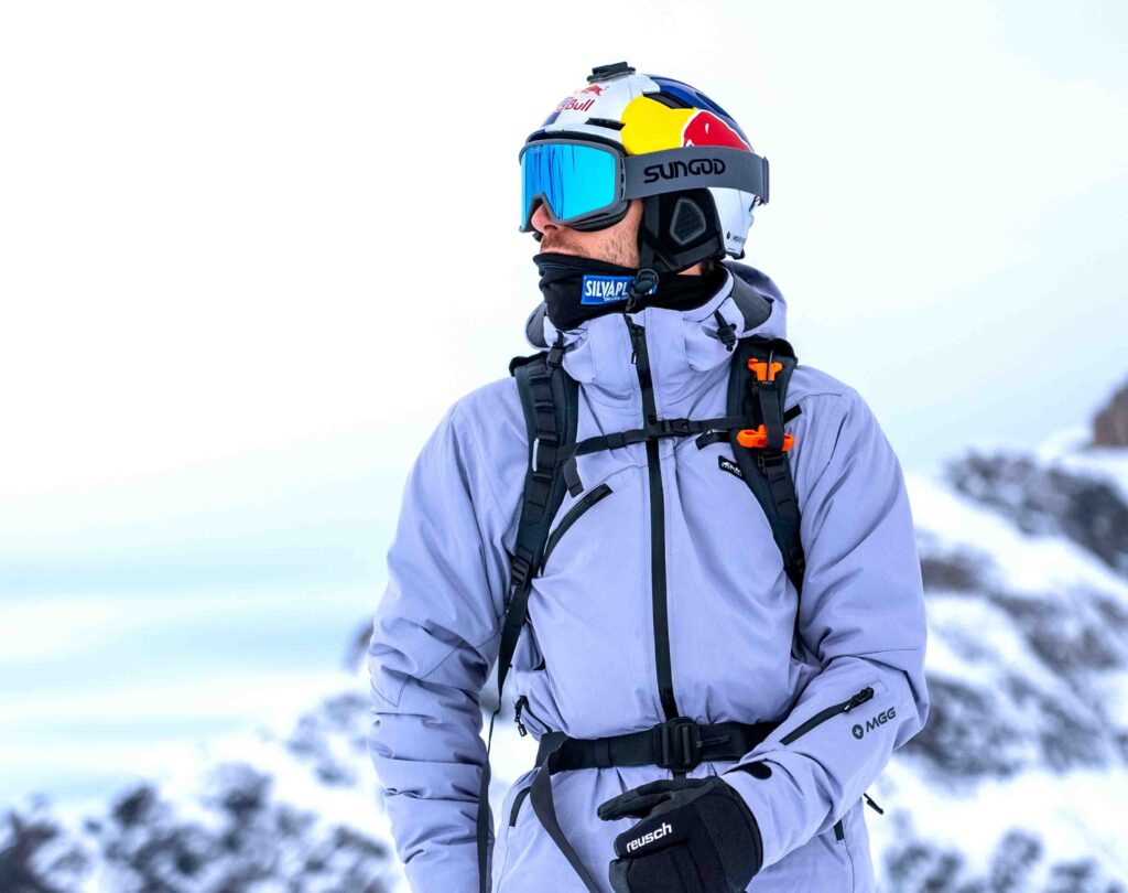 a skier in Sungod goggles poses on the mountain, the background blurred