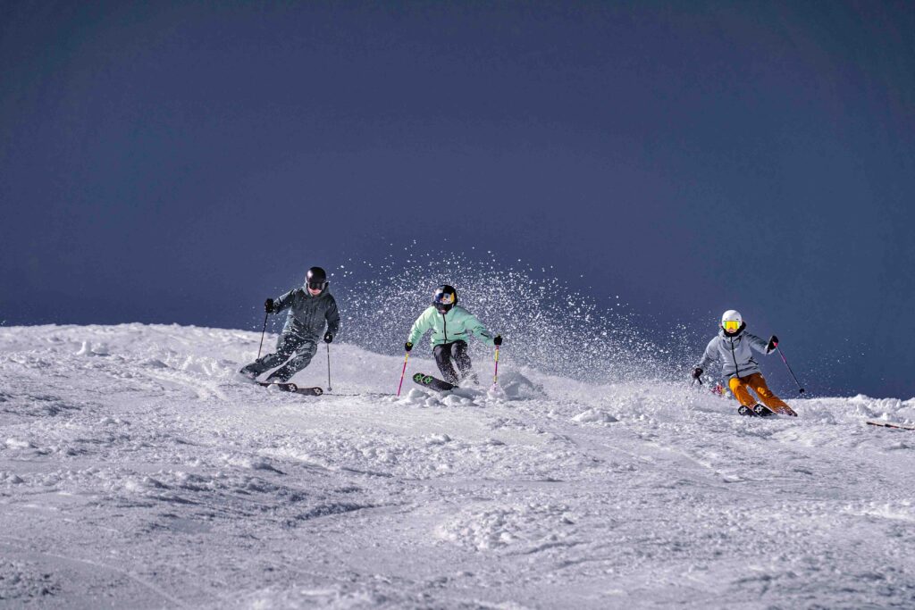 three skiers on chop snow